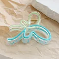 Detail of a wavy acrylic hair claw with blue-green stripes and gold spring on craft paper - Light Coffee