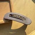 Macro detail of matte grey hair clip on wooden tray with natural sunlight shadows - Purple