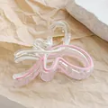 Macro view of butterfly hair claw clip with pink wave pattern and gold metal spring - Milky White