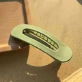 Detailed view of a sage green matte hair clip resting on a wooden tray and textured background - Light Green