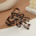 Eleganter Haarklammer mit bernsteinfarbenem Leopardenmuster auf minimalistischem Hintergrund - Eleganter Ineinander Verschlungener Bandformstil (K)