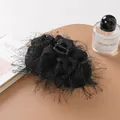 Detail of elegant black ostrich feather hair claw clip with subtle silver sparkles on desk - Black
