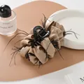 Detail einer eleganten Haarklammer aus champagnerfarbenem Satin mit schwarzen Federn - Khaki