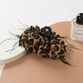 Pinza de pelo con estampado de leopardo y plumas negras en superficie elegante - Leopardo Marrón