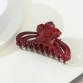 Macro view of a glossy deep red hair claw clip with a detailed flower ornament - Sun Flower / Burgundy