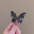 Gros plan d'une pince à cheveux papillon avec strass noirs et finition scintillante - Noir