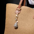 Golden shell keychain with natural conch pendant and white flowers on a woven bag - Leaf Pearl Conch Style (HWBC766-3)