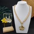 Detailansicht der goldenen Blumenhalskette und Perlenohrringe auf einem Schmuckhalter - Beige (HWNX9344-6)