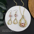 Hawaiian scroll jewelry set with gold metal finish and purple pearls on a white stand - Purple Pearl Hollow Teardrop Style (HWNX9438-2)