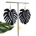 Detail van zwarte monstera oorbellen met gouden haakjes op tropische displaystandaard - Hol Ontwerp 2 (HWX1514-1) / Zwart