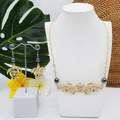 Détail d'une parure tortue dorée avec perles irisées et décor de fleurs tropicales - Style Perle Bleu Foncé