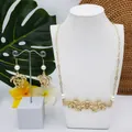 Parure de bijoux tortue dorée avec perles sur présentoir à feuilles tropicales - Style Perle Blanche