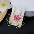 Detail of hollow monstera leaf earrings with green pearls on an Aloha display card - Yellow Green Bead Style (HWX693-5)