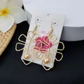 Golden monstera leaf drop earrings with pearl detail on a white tropical display stand - Champagne Pearl Style (HWX693-7)