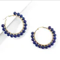 Detailed view of gold wire-wrapped hoop earrings with deep blue lapis lazuli beads - Lapis Lazuli
