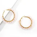 Macro shot of handmade gold wire-wrapped hoop earrings with pink crystal beads - Rose Quartz