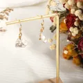 Detail of bohemian natural white stone earrings with gold wire wrap on a display stand - Howlite