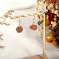 Detail of bohemian gold hook earrings with natural red goldstone on a display stand - Gold Sandstone