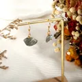 Detail of natural grey crystal earrings with gold wire wrap on a jewelry display stand - Labradorite