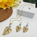 Macro detail of tropical monstera leaf jewelry set with blue faux pearls and gold chain - Light Blue Pearl Style (HWNX9484-19)