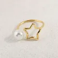 Detail eines verstellbaren Goldrings mit hohlem Stern und Perle auf Sandtextur - Gold Weiße Perle Stern Stil (AWM_8175)