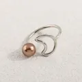 Detail eines silbernen offenen Rings mit Bronze-Perle und Wellendesign auf Stein - Silber Bronze Perle Wellen Stil (AWM_8180)