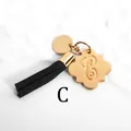 Detail of a golden metal pendant with letter C engraving and a black suede tassel charm - Letter C-Gold Tassel