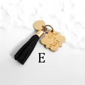 Detailed close-up of golden petal tag with engraved letter E and black suede tassel - Letter E-Gold Tassel
