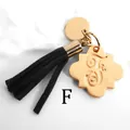 Macro shot of gold alloy clover pendant with letter F and black faux suede tassel - Letter F-Gold Tassel
