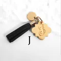 Detail of a black suede tassel keychain with a gold floral pendant and letter S engraving - Letter J-Gold Tassel
