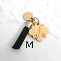 Macro shot of golden letter M charm with black silk tassel and polished metal finish - Letter M-Gold Tassel