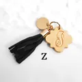 Detail of gold letter S pendant with a black tassel on a white marble background - Letter Z-Gold Tassel