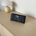 Women's black long zip wallet with V-stitched quilted pattern on wooden surface - Black