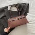 Bolso de hombro marrón oscuro mate con hebillas doradas y asas largas cilíndricas de cuero - Marrón