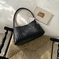 Sac à bandoulière tressé noir élégant exposé sur une chaise design de style - Noir