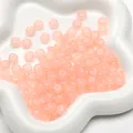 Translucent pink glass rondelle beads displayed in a white star-shaped ceramic dish - Apricot