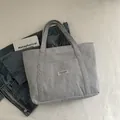 Light gray corduroy tote bag with front pocket and shoulder straps on a clean white background - Dark Gray