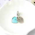 Dettaglio del charm cuore in smalto blu e ciondolo cuore traforato con micro zirconi - Blu Zaffiro