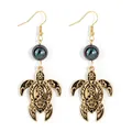 Macro shot of gold turtle earrings with dark iridescent pearls and hollow patterns - Iridescent Black Bead (HWNX9436-1)