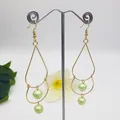 Detail of gold drop earrings with irregular metal frames and light green pearls - Light Green Style