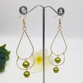 Detail view of double-layered gold drop earrings with olive green faux pearls and floral background - Olive Green Style