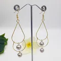 Macro view of gold teardrop geometric earrings with hanging silver polished beads - Silver Bead
