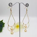 Close-up of golden double-layered pearl drop earrings with elegant tassel design - Cream Style