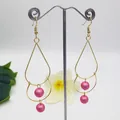 Detailed view of double layered gold drop earrings with pink pearl accents on a display stand - Light Pink