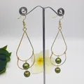 Detail of gold teardrop earrings with double green pearls on a metal display stand - Dark Green