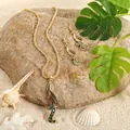 Detailed shot of abalone shell sunflower jewelry set on sand with tropical leaves - Streamlined Wave Style (HWNX2461)