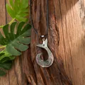 Close-up of shell fish hook pendant with tribal carvings on natural bark background - Ethnic Fish Hook Style (HWBN246)