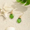 Handmade green sea glass drop earrings with gold wire wrap on white sand beach background - Green (HWG280-2)