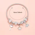 Detail of silver charm bracelet with princess crown, pink heart, and 18cm length scale - White