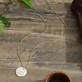Golden heart and shell round necklace on dark wood background with natural lighting - Heart Wave Style (HWBN975)